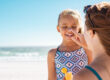 Mother applying suntan lotion on daughter face