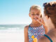 Mother applying suntan lotion on daughter face